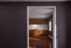 an open door leading into a kitchen with wood floors and cabinets on either side of the room