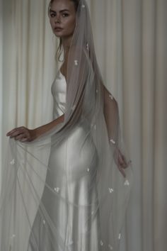 a woman in a white wedding dress with a veil over her head and hands on her hips