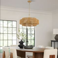 a dining room table with white chairs and a chandelier hanging from the ceiling