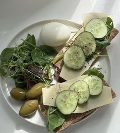 a white plate topped with cucumbers, cheese and other food on top of it