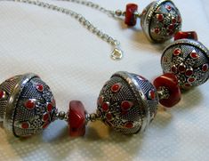 This is a beauty for any occasion. Four large round Bali beads with red enamel dots are paired with real coral discs. Each Bali bead is about 3 cm in diameter. Smaller silver beads and bead caps are in between the coral and Bali beads. The back of the necklace is simple chain, with a lobster clasp. The total length of the necklace is 27 1/2 inches or 70 cm. All metal is silver plated Handmade Silver Beaded Necklaces With Red Coral, Silver Necklace With Polished Red Coral Beads, Silver Jewelry With Round Red Coral Beads, Red Round Jewelry With Silver Beads, Red Round Silver Beaded Jewelry, Red Jewelry With Silver Beads, Spiritual Red Necklace With Silver Beads, Spiritual Red Necklaces With Silver Beads, Red Coral Necklace