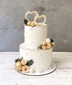 two tiered wedding cake decorated with white frosting and gold decorations on a plate