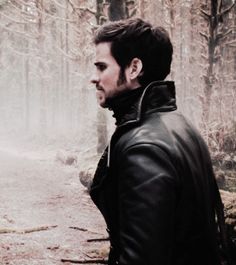 a man standing in the woods wearing a leather jacket