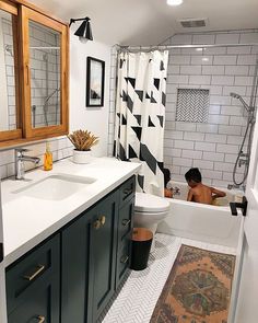 a bathroom with black and white tiles on the floor, shower curtain, rug, sink, and bathtub