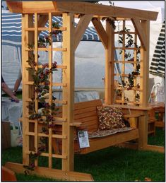 a wooden bench sitting in the grass under a gazebo