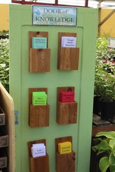 a green door with several notes attached to it and some plants in the back ground