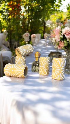 the table is covered with white linens and yellow napkins, which are decorated with pink flowers