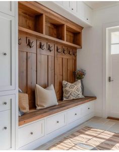 a wooden bench sitting in the middle of a room with white cupboards and drawers