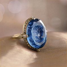 "As soon as this charming ring comes into your possession, you'll notice the details that contribute to its beauty. The intaglio is a reverse cameo with an incised, etched image and is handmade, using the very same process used by Bohemian glass makers of the last centuries. Beloved by Catherine the Great, intaglios were made in glass, agate, even lava -- all treasured for their exquisite detail. We set the intaglio into a delicate, yet sizeable ring design with an open bezel and under-gallery, Ring Blue Stone, Blue Amethyst, The Bling Ring, Michal Negrin, Ring Ruby, Blue Stone Ring, Antique Ring, Cameo Ring, Sweet Romance