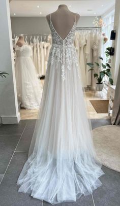 the back of a wedding dress on display in a bridal shop, with other gowns behind it