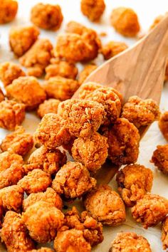 a wooden spoon filled with fried food on top of a table