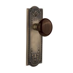 an antique style door handle with a black knob and ornate design on the front plate