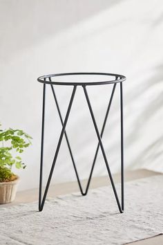 a small black metal table next to a potted plant