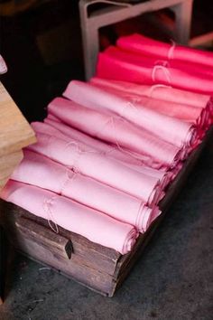 several pieces of pink cloth are stacked on top of each other in a wooden box