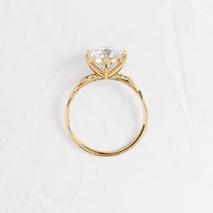 a gold ring with a single diamond on the center and side stones in the middle