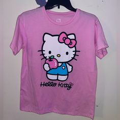 a pink hello kitty t - shirt with an apple in her hand and the words hello kitty on it