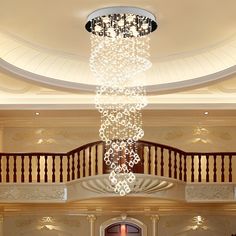 a chandelier hanging from the ceiling in a large room with stairs and railings