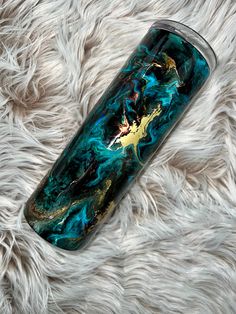 a blue and gold marbled glass tumbler sitting on top of a fluffy white blanket