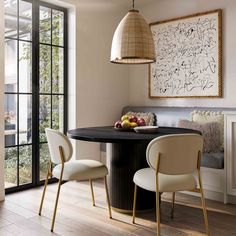 a dining room table with two chairs and a bowl of fruit on it