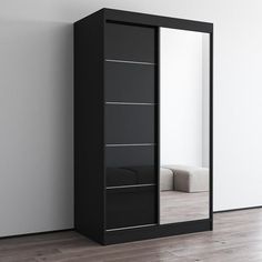 an empty room with a large mirror and black cabinet on the floor next to it