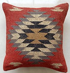 a red and black pillow sitting on top of a white wall