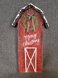 a red barn with a wreath on the door and merry christmas written in white letters