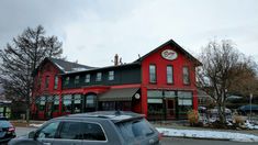 a car parked in front of a red building with a clock on it's side