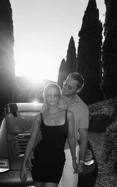 a man and woman standing in front of a car with the sun shining on them