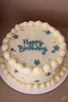 a birthday cake with frosting and blue flowers on it is sitting in a box