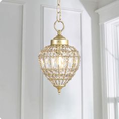 a golden chandelier hanging from the ceiling in a room with white walls and windows