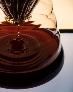 a close up of a glass vase on a table with water in the bottom and an object inside it