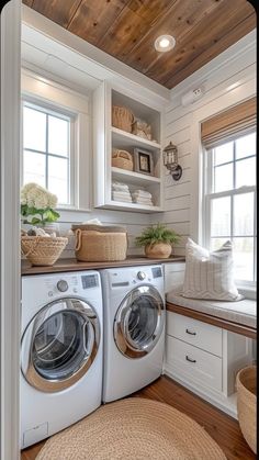 a washer and dryer in a room with wood floors, white walls and windows