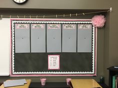 a bulletin board with pink pom poms on it