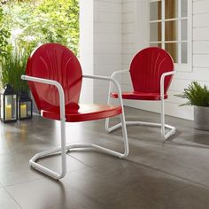 a red chair sitting on top of a cement floor next to a plant and window