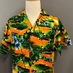 You are viewing a very cool Vintage Men's Cotton Blend Hawaiian or Aloha Shirt c1970s. This great looking shirt is made of a medium weight cotton blend cloth with a printed floral and palm tree pattern in shades of orange, green, gold, yellow and brown. Details include splayed camp collar, 4 button placket (with clear plastic buttons), 10" short sleeves, left patched chest pocket and straight hem. Dates from likely the late 1970s. Retains maker's label at neckline (Hukilau Fashions, Honolulu). F Casual Hawaiian Shirt With Retro Print And Camp Collar, Printed Cotton Hawaiian Shirt With Camp Collar, Casual Hawaiian Shirt With Retro Print For Vacation, Multicolor Cotton Hawaiian Shirt For Vacation, Multicolor Tropical Cotton Camp Shirt, Cotton Hawaiian Shirt With Retro Print And Camp Collar, Hawaiian Cotton Camp Shirt With Graphic Print, Casual Hawaiian Shirt With Vintage Print And Camp Collar, Cotton Hawaiian Camp Shirt With Graphic Print