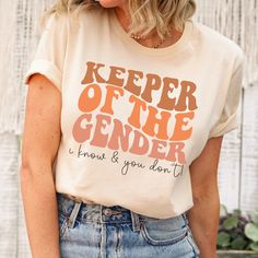 a woman wearing a t - shirt that says keeper of the genderer and has her hands in her pockets