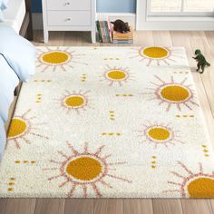 a white rug with orange and yellow flowers on it in a bedroom area next to a bed