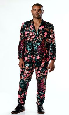 a man in a floral suit poses for the camera with his hands on his hips