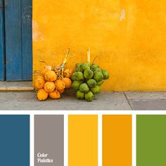 a bunch of fruit sitting on the ground in front of a yellow building with blue doors