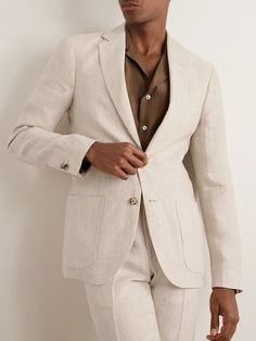 a man wearing a white suit and brown shirt