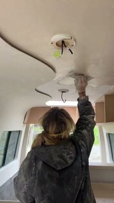 a woman is working on the ceiling in her home