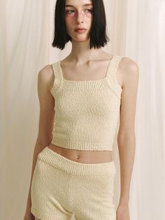 This product is a crop knit sleeveless top that offers a contemporary and cozy addition to any wardrobe with its textured fabric and cropped cut. The piece is designed for a snug fit that highlights the waist, making it an excellent partner to high-waisted bottoms. - The top features a delicate knit pattern that adds a touch of elegance to the simple silhouette.- Its cropped length is on-trend, perfect for pairing with various high-waisted garments.- The sleeveless design makes it ideal for layering under jackets or wearing alone in warmer weather.- Constructed with comfort in mind, the soft knit material provides a gentle feel against the skin. Chic Textured Knit Fitted Tank Top, Chic Fitted Textured Knit Tank Top, Fitted Textured Knit Sleeveless Top, Fitted Sleeveless Textured Knit Top, Fitted Cropped Beige Tank Top, Chic Knit Tank Crop Top, Fitted Cropped Top In Textured Knit, Chic Fitted Tank Top With Cropped Hem, Chic Sleeveless Crop Top For Loungewear