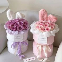 two stuffed animals sitting next to each other on a white couch with pink and purple flowers in them