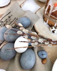 an easter cake with frosting on top surrounded by blue eggs and almonds, along with other decorations