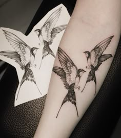 two birds on the arm with one bird flying away from it's head and another bird sitting in front of it