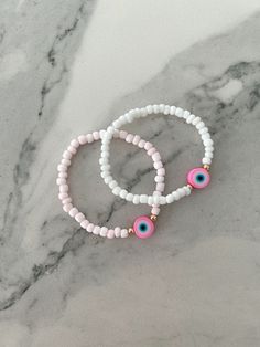 This pink evil eye bracelet is designed to bring anyone who wears it positive energy & protection. Available with either white or light pink 4mm glass beads Materials Used: White/Light Pink Beads: Glass Gold Beads: 14K gold plated Eye: Polymer Clay Stretch bracelet: Made to order in your wrist size Customization available: If you would like to adjust something in the design feel free to message me and I will do my best to accommodate! Pink Bead Bracelet, Pink Evil Eye, Protective Eye, Greek Eye, Protection Eye, Bracelet Craft, Energy Protection, Bracelets Ideas, Bracelet Craft Diy