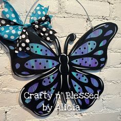 a black and blue butterfly with polka dots on it's wings hanging from a brick wall