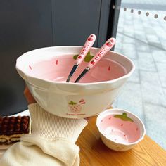 a bowl with strawberries in it and three spoons sticking out of the top