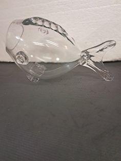 a clear glass fish sitting on top of a black table next to a white wall