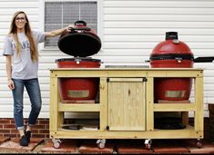 a woman standing in front of two large red pots on top of a wooden cart